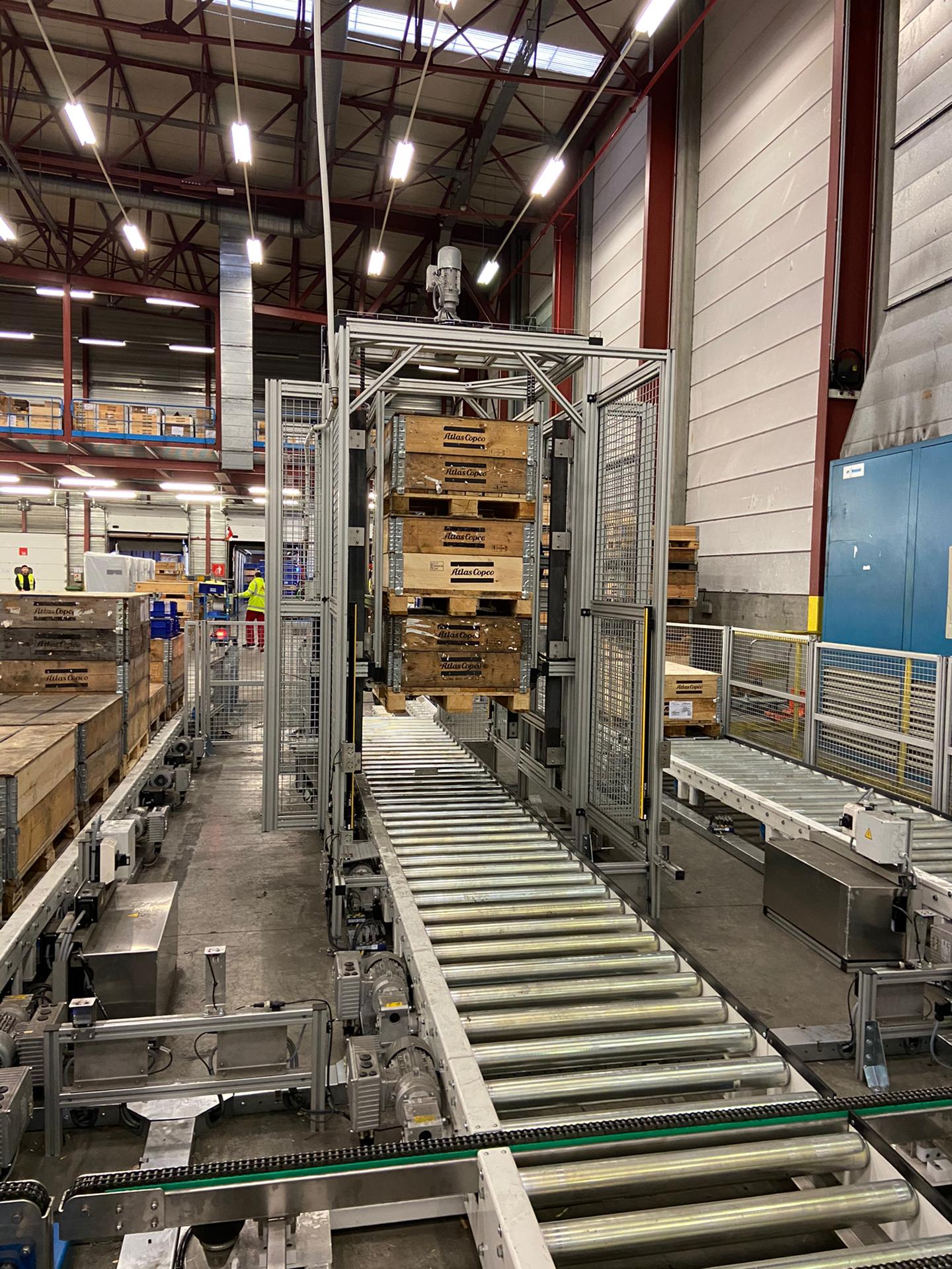 er een rollenbaan - met aluminium rollen en blauwe zijkanten - en dat in een magazijn. Dynamic Conveyor Solutions ondersteunt hun klanten ook met de installatie en montage van soortgelijke conveyors.